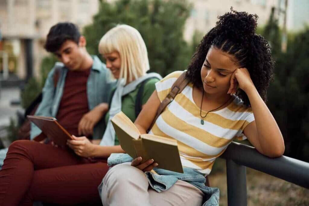  czarnoskóra kobieta czytająca książkę na ławce 